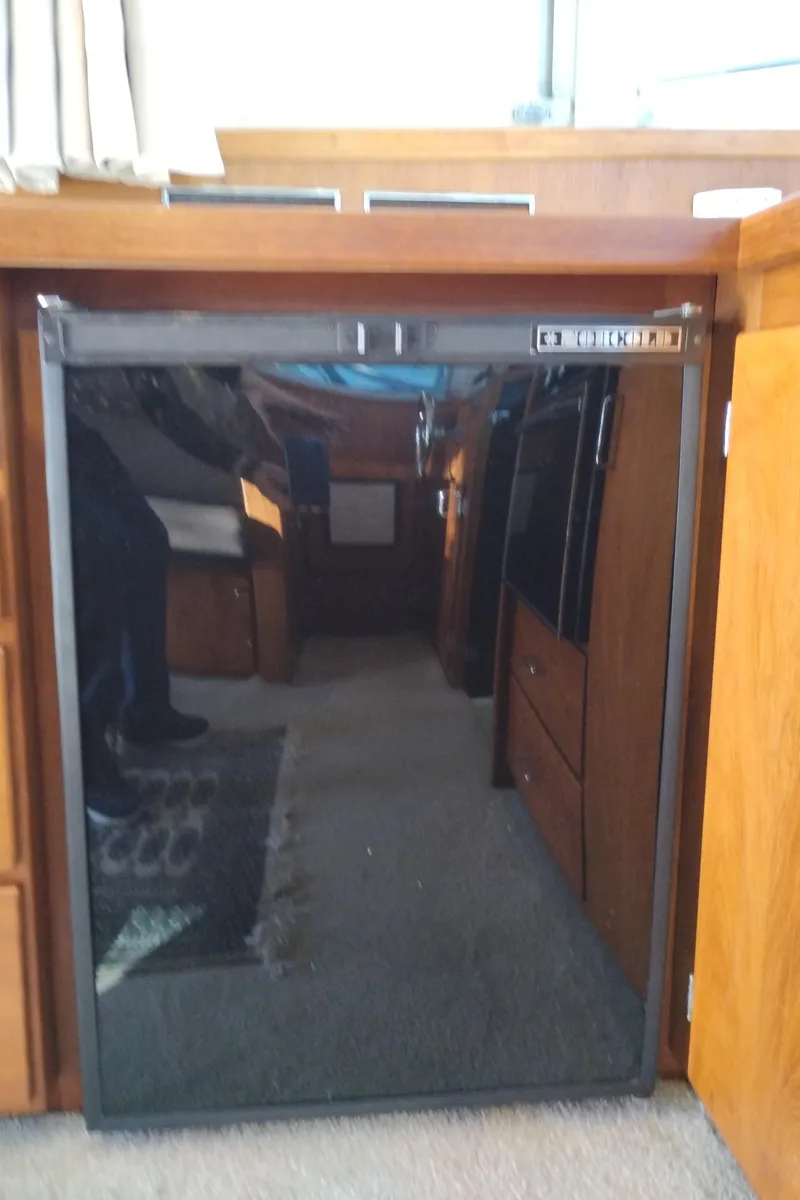 Slide: The Image of 1978 Bertram 33 Convertible interior with wooden cabinetry and a compact refrigerator. - 24