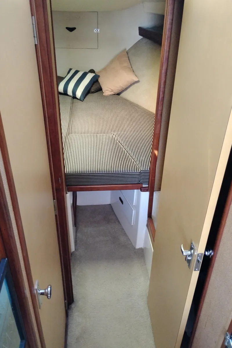 Slide: The Image of 1978 Bertram 33 Convertible cabin interior with striped bedding and pillows. - 41