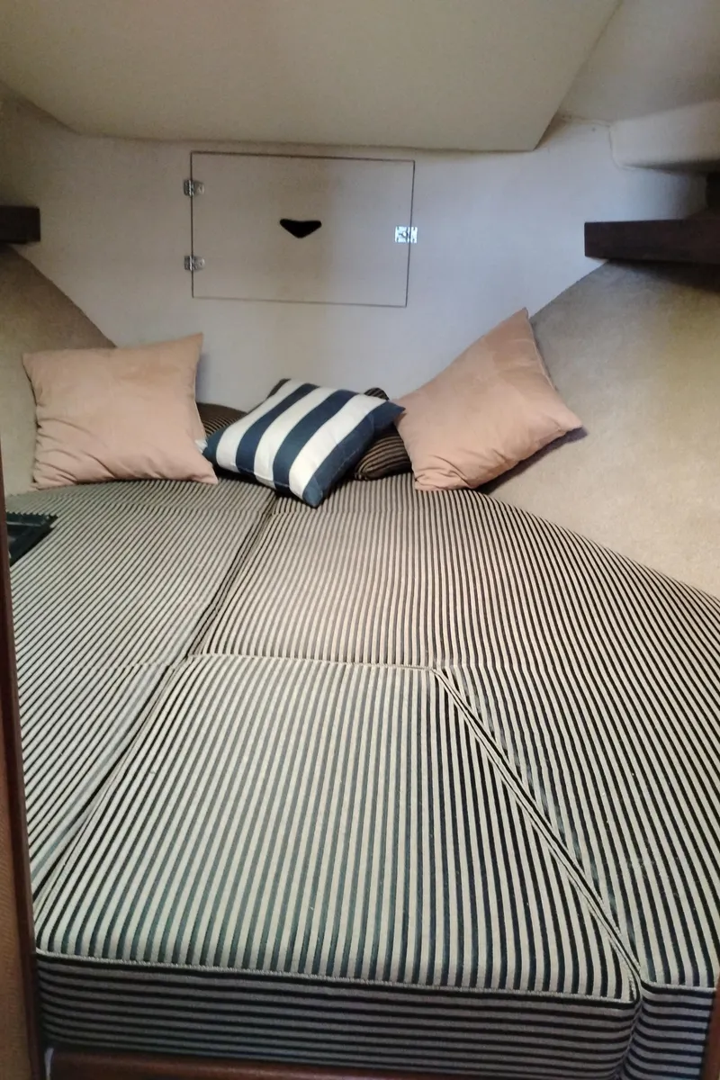 Slide: The Image of 1978 Bertram 33 Convertible cabin with striped bedding and cushions. - 42