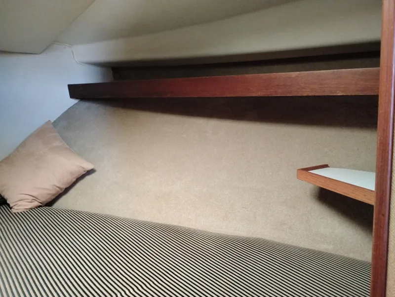 Slide: The Image of 1978 Bertram 33 Convertible cabin interior with striped bedding and wooden shelf. - 43