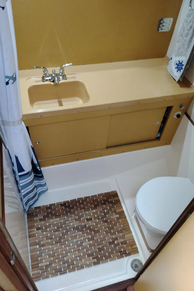 Slide: The Image of 1978 Bertram 33 Convertible boat bathroom with yellow sink, toilet, and nautical-themed decor. - 47