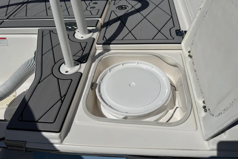 Slide: The Image of 2022 Robalo 266 Cayman boat storage compartment with open lid and bucket inside. - 36