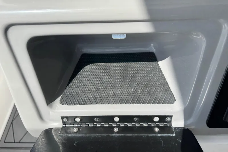 Slide: The Image of Storage compartment in 2022 Robalo 266 Cayman boat, featuring a textured mat and sturdy hinge. - 50