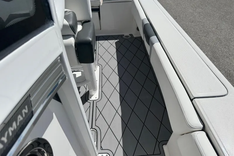 Slide: The Image of 2022 Robalo 266 Cayman boat interior with cushioned seating and diamond-patterned flooring. - 70
