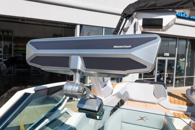 Slide: The Image of 2026 MasterCraft X24 boat rear view, showcasing seating and deck design in a parking lot. - 12