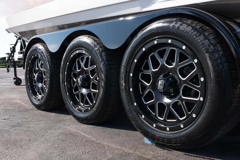 Slide: The Image of 2026 MasterCraft X24 trailer with stylish black alloy wheels in a parking lot. - 25