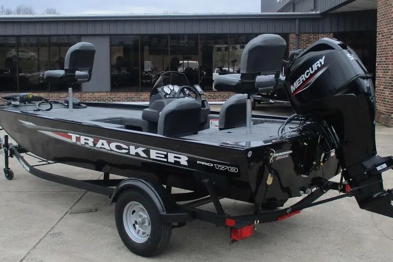 Slide: The Image of 2026 Tracker Pro 170 boat with Mercury engine, parked outside a building. - 2