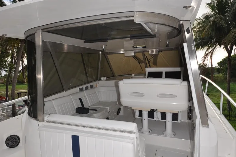 Slide: The Image of 2009 Intrepid 430 Sport Yacht interior with white seating and helm, surrounded by palm trees. - 9