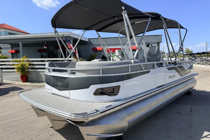 The Image of 2026 Avalon 2385 Venture 85 VRB Tri Toon boat with canopy, parked outdoors. - 1