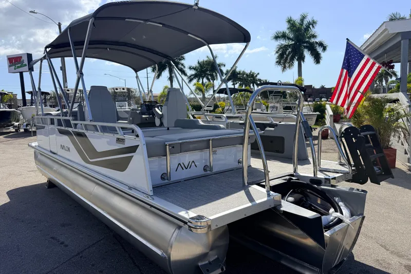 Slide: The Image of 2026 Avalon 2385 Venture 85 VRB Tri Toon boat with American flag, parked outdoors. - 8