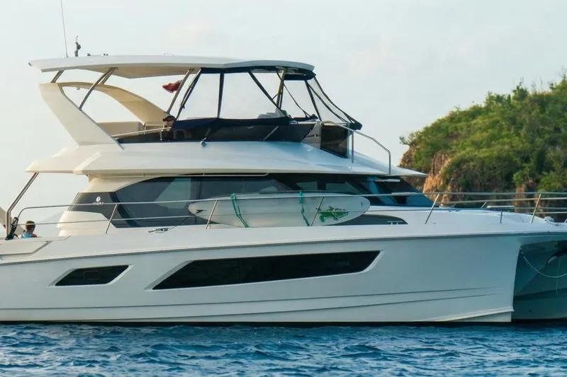 The Image of 2020 Aquila 44 Yacht cruising on blue waters near a lush green island. - 0