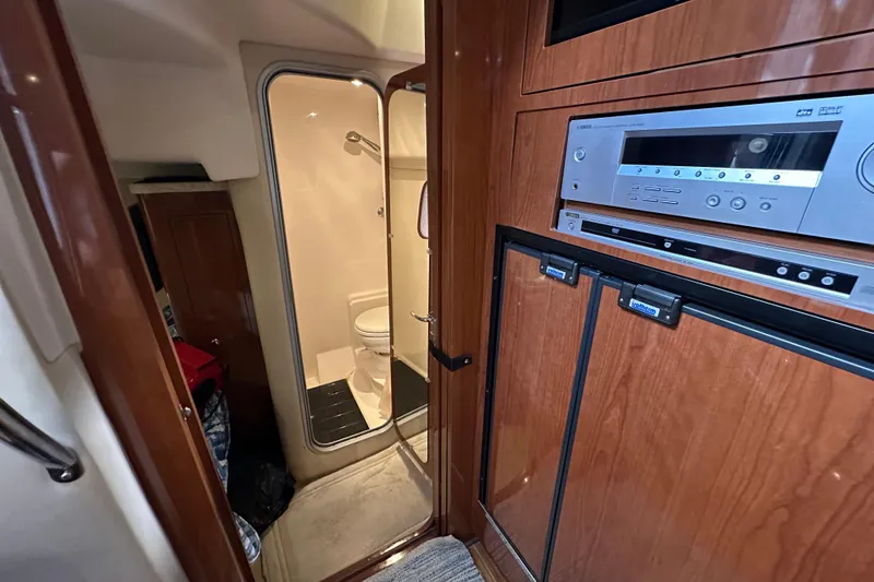 Slide: The Image of Interior of 2008 Regal Commodore 4060 yacht, featuring a compact bathroom and entertainment system. - 52