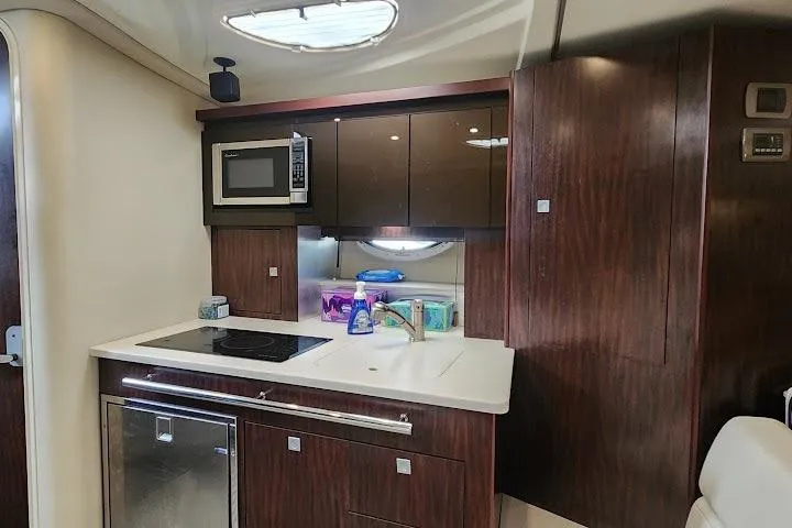Slide: The Image of 2015 Monterey 335 Sport Yacht kitchen with microwave, stove, and modern cabinetry. - 7