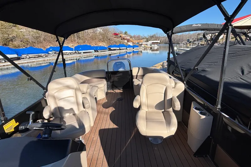 Slide: The Image of 2023 Bentley Pontoons 220 Navigator interior with beige seating, docked at a marina. - 10