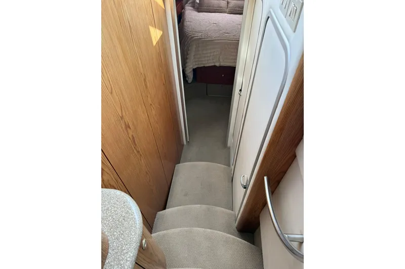 Slide: The Image of Interior view of 1999 Maxum 4600 SCB yacht, featuring carpeted stairs and wooden paneling. - 16