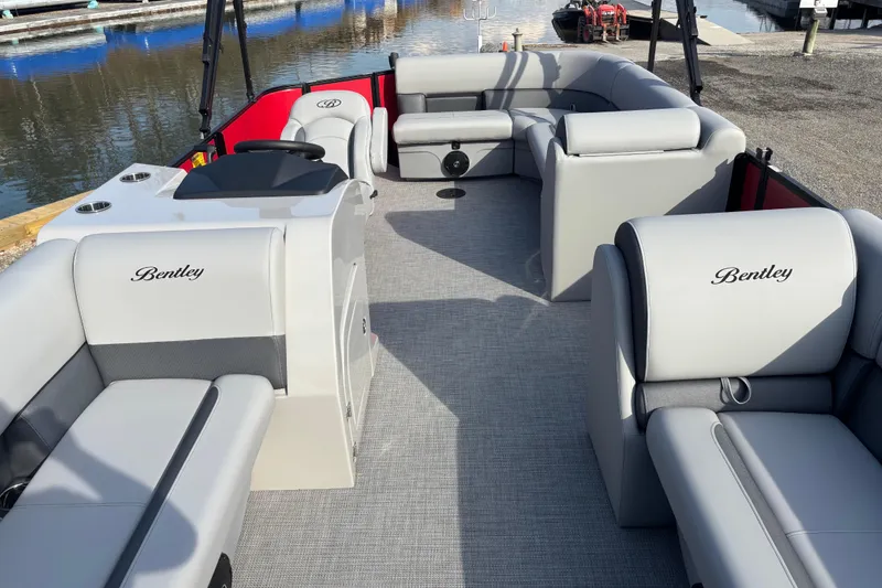 Slide: The Image of 2026 Bentley Pontoons Legacy 220 Cruise XL with luxurious seating at a marina. - 2