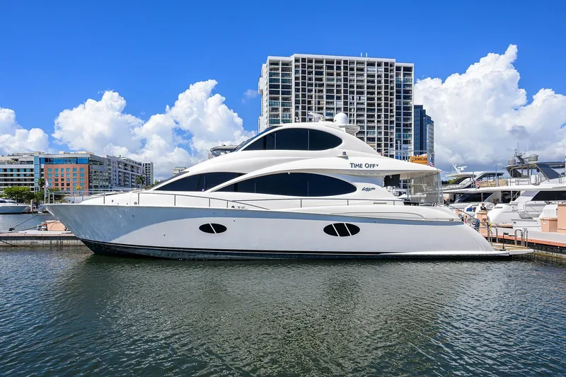 The Image of 2005 Lazzara 68 Enclosed Bridge yacht docked in a marina, cityscape background. - 1