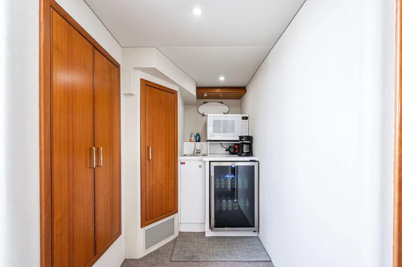 Slide: The Image of Compact kitchenette in 2001 West Bay Sonship yacht with microwave, fridge, and wooden cabinets. - 34