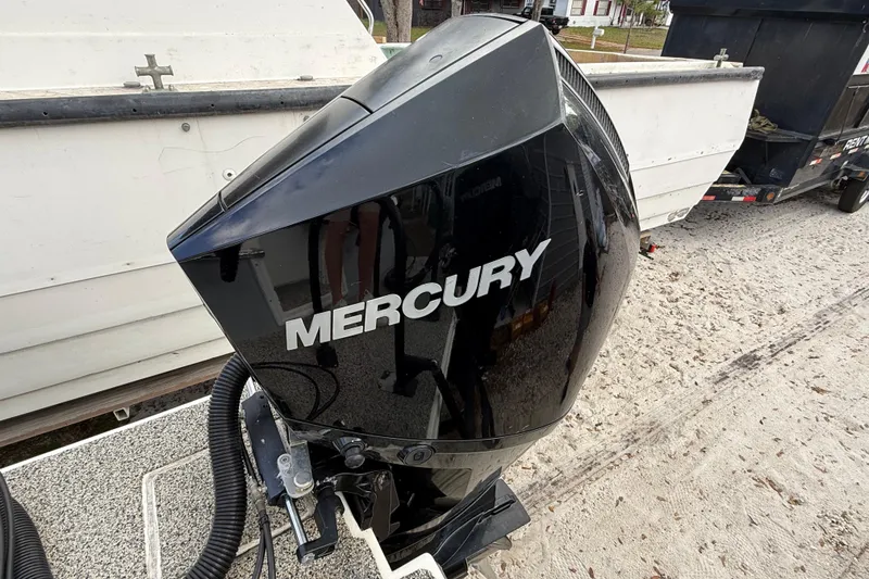 Slide: The Image of Black Mercury outboard motor on a 2022 Eastward 30 boat, parked on sandy ground. - 111