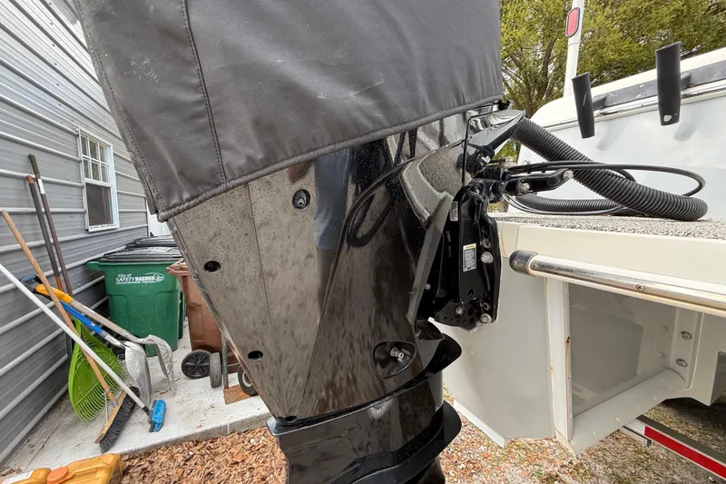 Slide: The Image of Outdoor view of a 2022 Eastward 30 boat motor, partially covered, near a garage. - 123