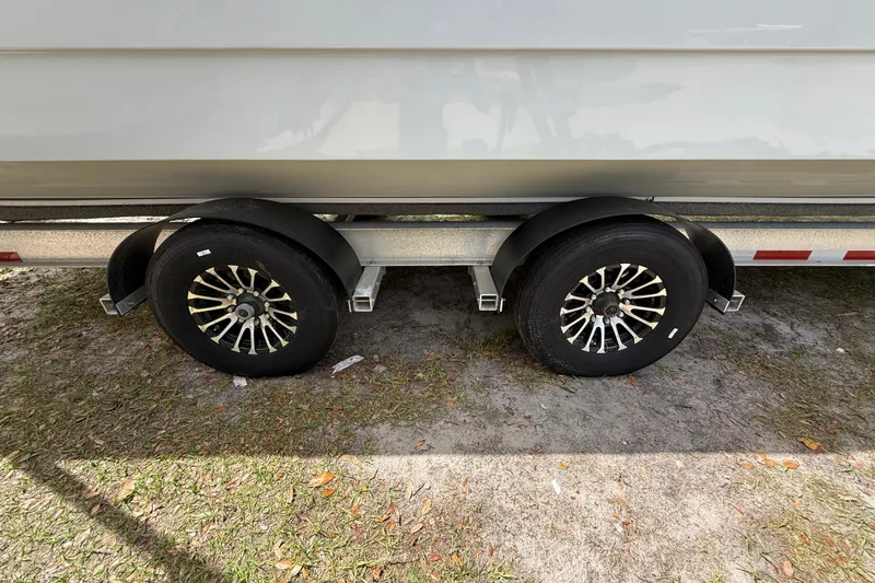 Slide: The Image of Trailer wheels of a 2022 Eastward 30 boat on grass surface. - 21