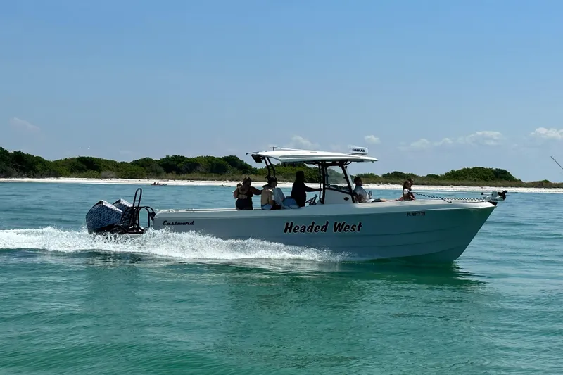 Slide: The Image of Eastward 30 boat cruising on clear water near a sandy beach, 2022 model. - 4