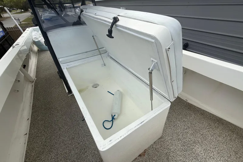 Slide: The Image of Open storage compartment on a 2022 Eastward 30 boat, featuring a white interior and hydraulic supports. - 43