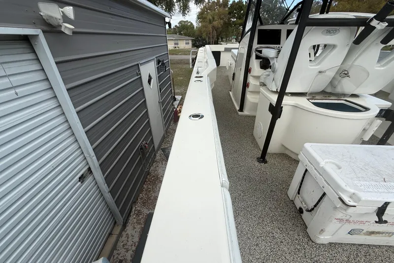 Slide: The Image of 2022 Eastward 30 boat beside a metal shed, showcasing deck and seating area. - 93