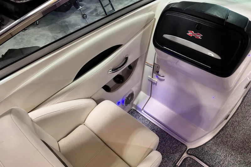 Slide: The Image of 2014 Chaparral 287 SSX boat interior with white seating and storage compartment. - 10