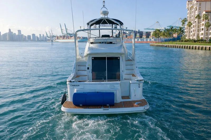 Slide: The Image of 2004 Carver 420 Mariner yacht cruising in a scenic harbor with city skyline. - 10