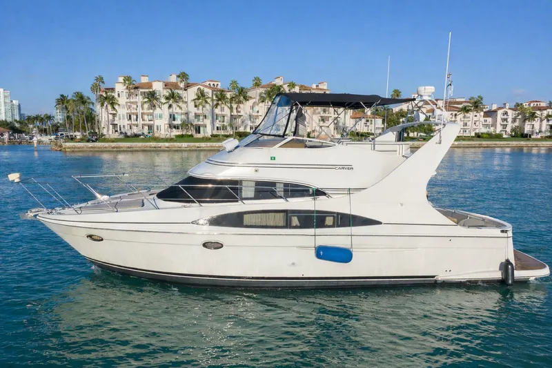Slide: The Image of 2004 Carver 420 Mariner yacht on calm water, with coastal buildings in the background. - 2