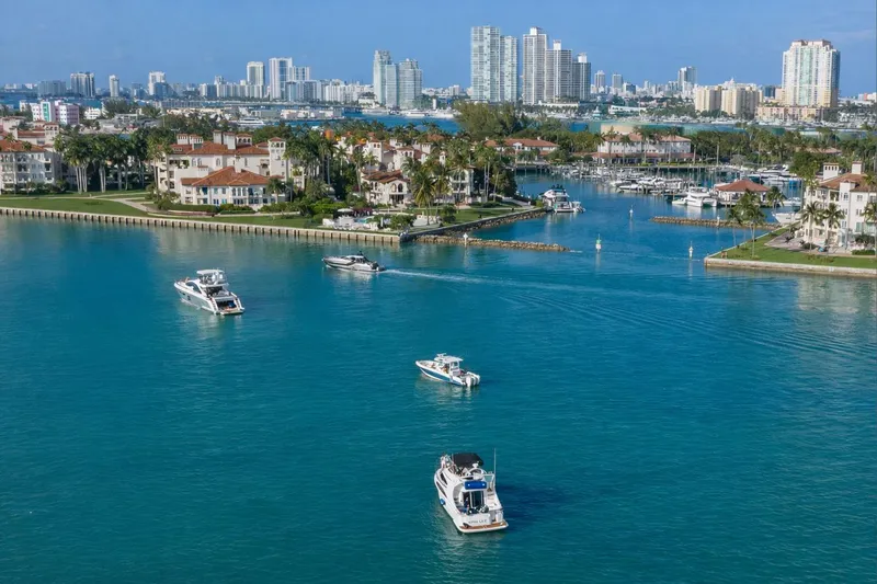 Slide: The Image of Boats, including a 2004 Carver 420 Mariner, cruising in a scenic coastal city marina. - 22