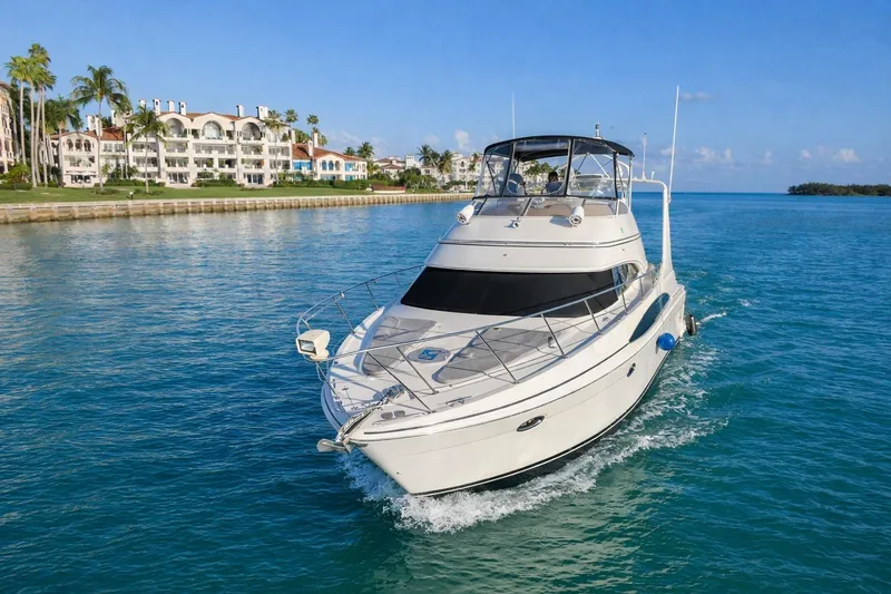 Slide: The Image of 2004 Carver 420 Mariner yacht cruising near waterfront luxury homes. - 6