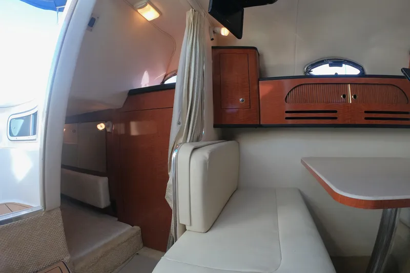 Slide: The Image of 2004 Sea Ray Sundancer 280 cabin interior with seating and wooden cabinetry. - 13