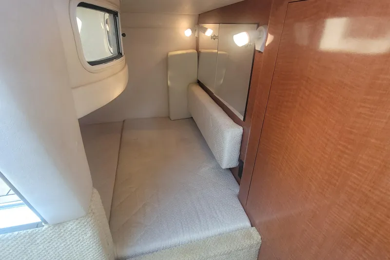 Slide: The Image of 2004 Sea Ray Sundancer 280 cabin interior with cozy bed and wooden paneling. - 14