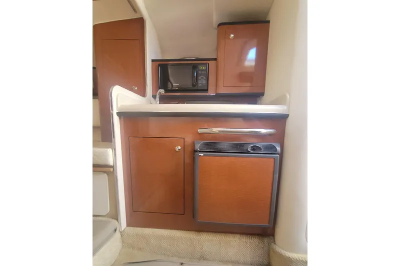 Slide: The Image of 2004 Sea Ray Sundancer 280 galley with microwave, fridge, and wooden cabinetry. - 16