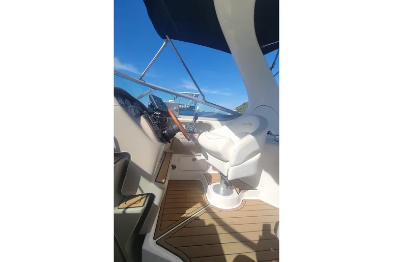 Slide: The Image of 2004 Sea Ray Sundancer 280 helm with white captain's chair and wooden deck. - 23