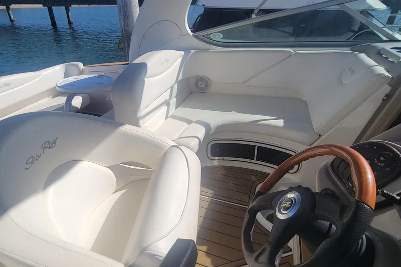 Slide: The Image of 2004 Sea Ray Sundancer 280 interior with white seating and wooden steering wheel. - 26