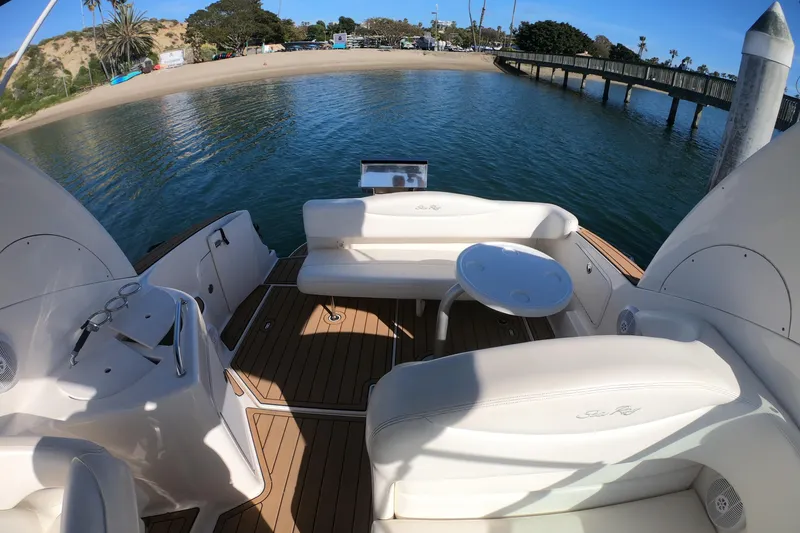 Slide: The Image of 2004 Sea Ray Sundancer 280 boat interior with seating and table, docked near a sandy beach. - 28