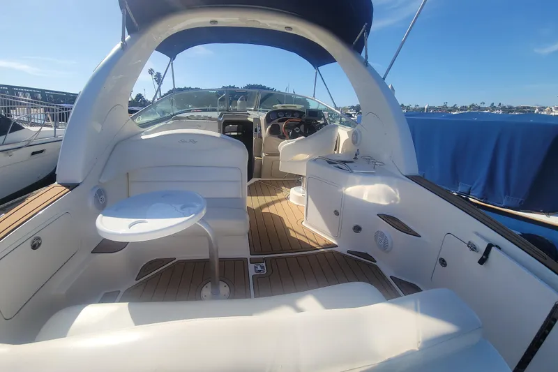 Slide: The Image of 2004 Sea Ray Sundancer 280 interior with seating and helm, docked under clear skies. - 5