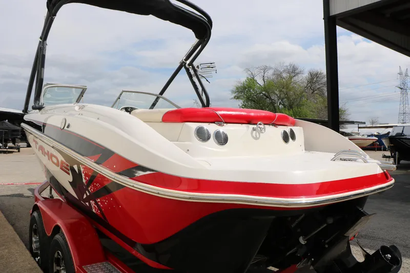 Slide: The Image of 2010 Tahoe Q7i boat with red and white design, parked outdoors. - 16