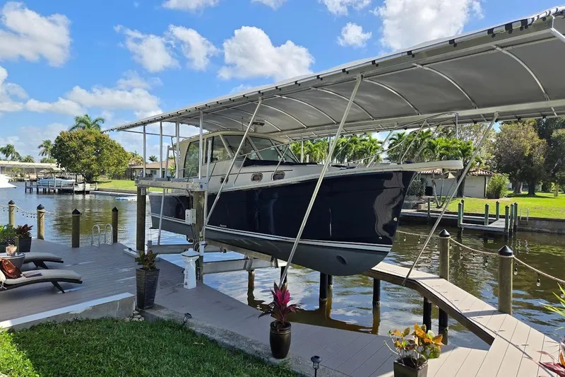The Image of 2009 Mainship Pilot 31 boat docked under a canopy on a sunny day. - 0