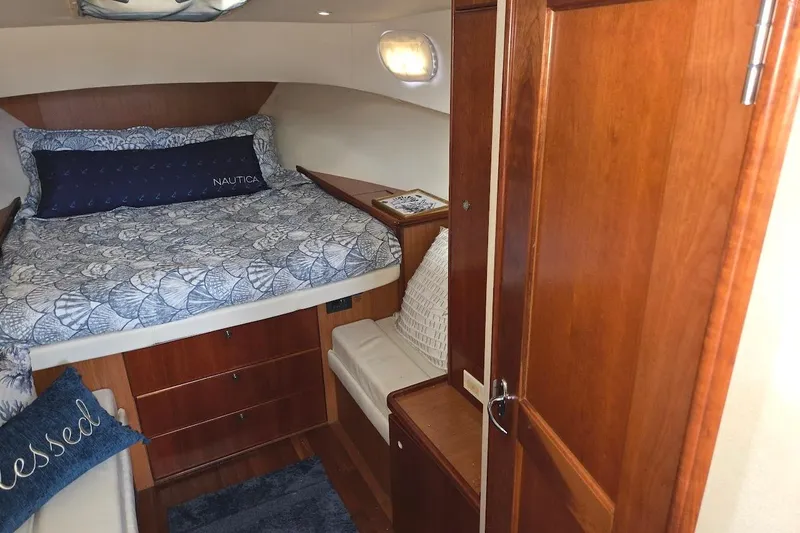 Slide: The Image of 2009 Mainship Pilot 31 cabin interior with cozy bed and wooden furnishings. - 14