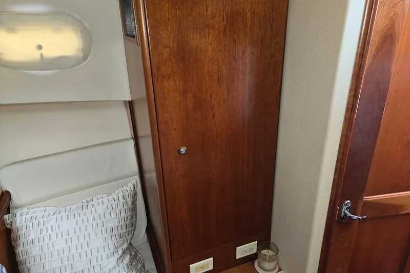 Slide: The Image of Interior of 2009 Mainship Pilot 31, featuring wooden cabinetry and a cozy sleeping area. - 16