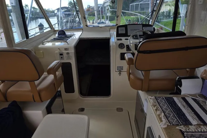 Slide: The Image of 2009 Mainship Pilot 31 boat interior with helm, tan seats, and navigation equipment. - 2