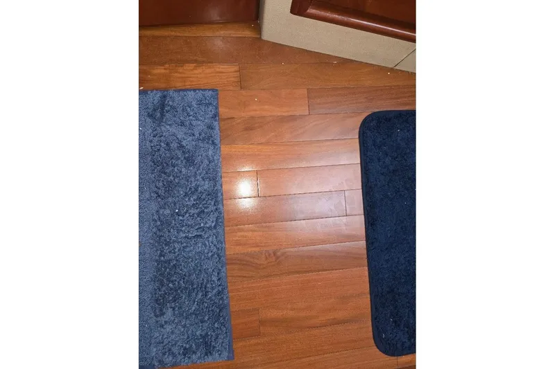 Slide: The Image of Wooden floor with blue rugs on a 2009 Mainship Pilot 31 boat. - 24