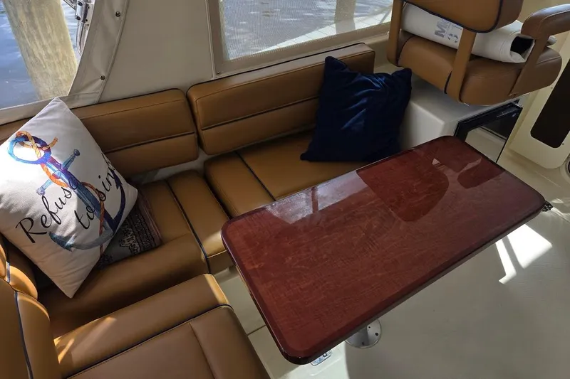 Slide: The Image of Interior of 2009 Mainship Pilot 31 with brown seating, wooden table, and nautical-themed pillow. - 29