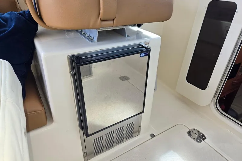 Slide: The Image of 2009 Mainship Pilot 31 interior with compact refrigerator and tan seating. - 37