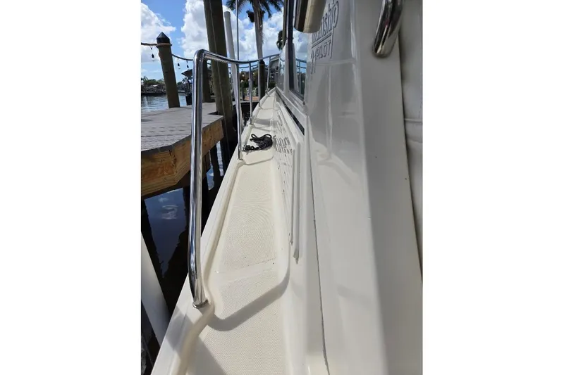 Slide: The Image of 2009 Mainship Pilot 31 boat deck with railing, docked by the water. - 56
