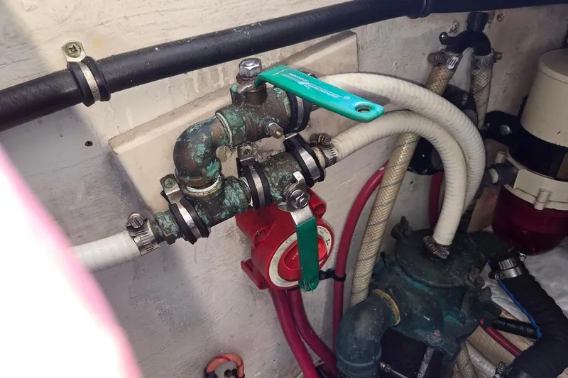 Slide: The Image of Engine room plumbing of a 2009 Mainship Pilot 31 boat, featuring pipes and valves. - 74